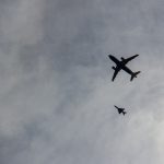 Team plane escorted by two fighter jets